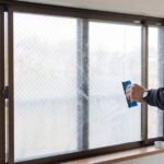 網入りガラスにシートを貼っている男性